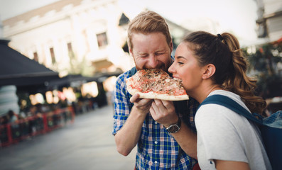 Happy students eating pizza on street