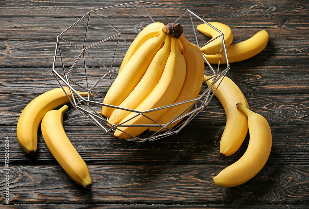 Basket with yummy bananas on wooden background