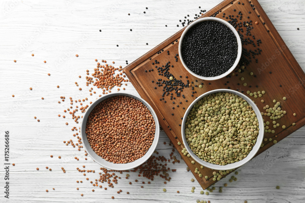 Bowls with different types of lentils on wooden table