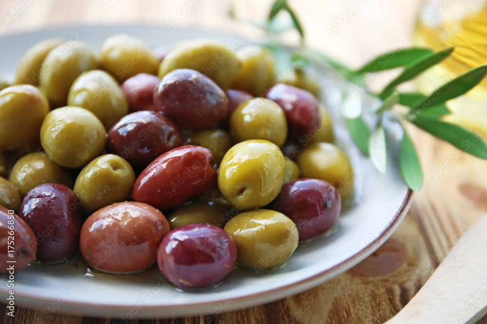 Plate with canned olives on table, close up