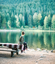 Girl Sitting On Picnic Table At Lake