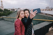 © Photodrive - Selfie of two young girls on city background. Spending good time together on roof, unusual places for rest and entertainment, open space leisure and friendship concept