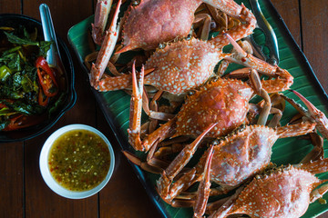 steamed flower crab on banana leaf pattern plate with spicy sauce from top view