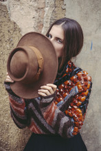 Woman Wearing Colorful Clothes And A Hat In Front Of A Vintage Wall
