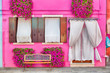 Pink house with pink flowers and plants. Nice bench under windows. Colorful house in Burano island near Venice, Italy