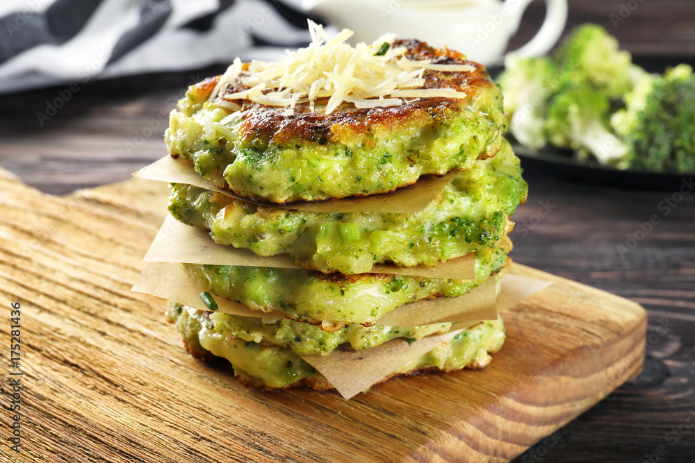 Wooden board with delicious broccoli pancakes on table