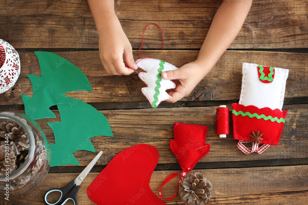 Child making felt Christmas fir tree at table