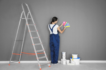 Sticker - Female decorator holding color palette samples near grey wall