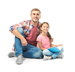 Canvas Print - Young man and his little daughter reading book on white background