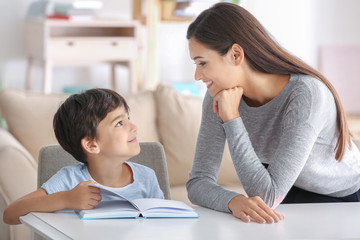 Wall Mural - Young woman and her little son reading book at home