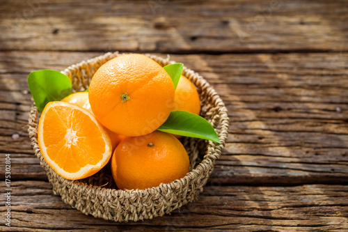 Zdjęcie XXL Świeże pomarańczowe owoc w koszu na drewno stole.