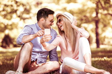 Wall Mural - Young couple making selfie with mobile phone in the park