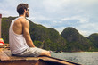 © anderpe - Handsome male cruising on retro wood boat by Andaman sea and behind him you can see Ko Phi Phi Lee Island in full glory. He's turned his back and enjoying the view.