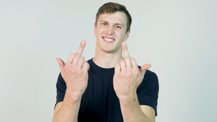 Young Man Showing Middle Finger Isolated on White. Young angry man with black t-shirt looking at camera and showing two middle finger