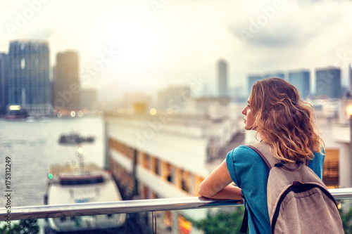 Fotografía ourist woman on background of a big city with skyscrapers, looking at the sunset