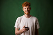 © Drobot Dean - Portrait of young smiling redhead bearded young man, holding mobile phone
