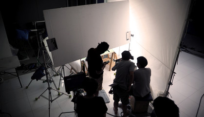 Film crew team are shooting video commercial with professional equipment such as ultra high definition digital camera and many big lighting and soft box on pan-tilt head tripod for best production.