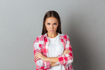 Wall Mural - Photo of beautiful serious woman in checkered shirt standing with arms folded