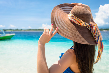 Woman wearing sun hat at beach by the ocean relaxing in her vacation