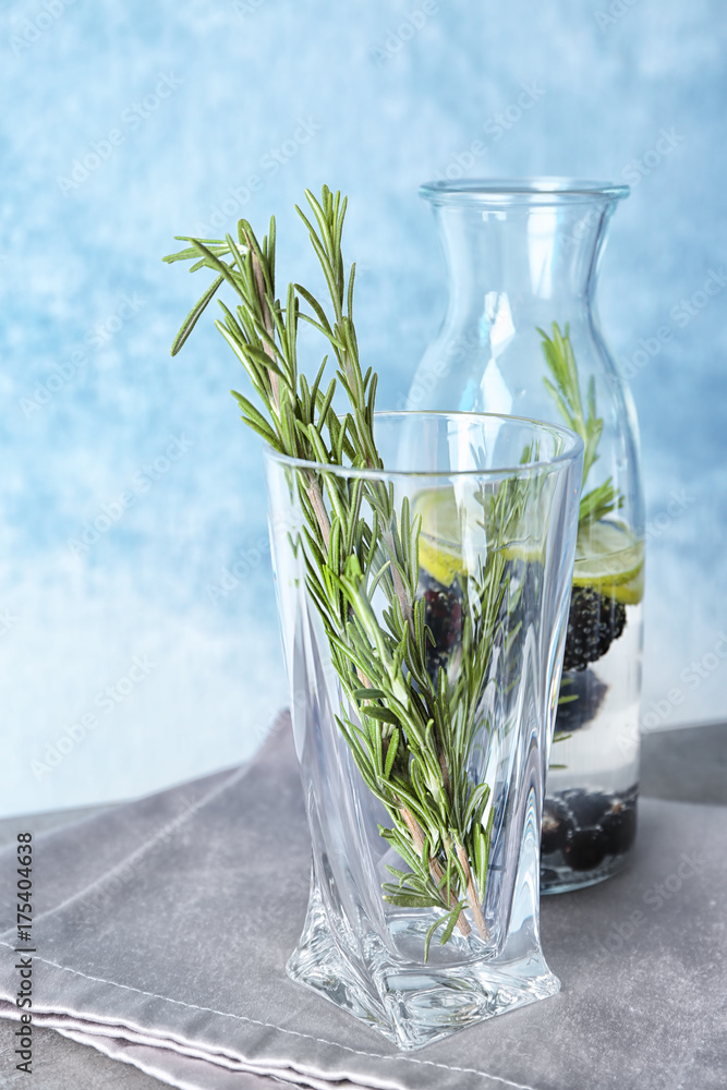 Glass with fresh rosemary twigs on table