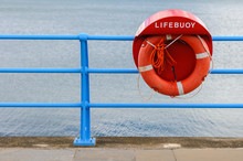 Red Lifering Life Preserver, Live Saver On A Rope Beside The Sea.