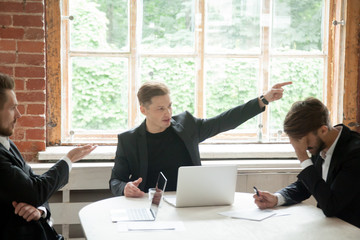 Wall Mural - Strict boss, telling upset male employee to leave meeting room during briefing, pointing his finger to the way out. Executive team member scolding colleague, CEO dismissing coworker in front of team.