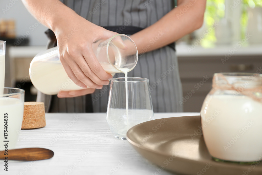 Woman pouring hemp milk into glass on table