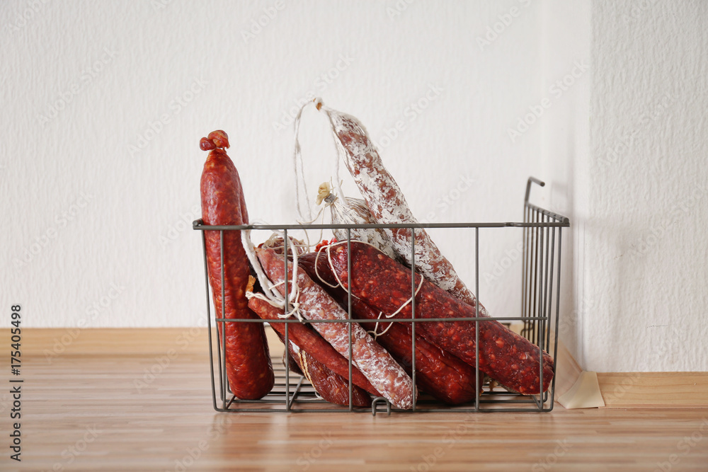 Smoked sausages in metal basket on floor