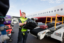 Worker Stacking Bags On Trailer At Runway