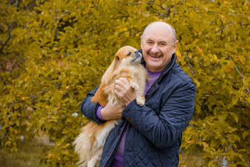 Senior man with a dog on a walk in city park having fun together. Old man and his best friend