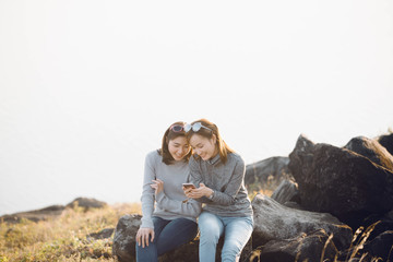 two Asia woman Friends using smart phone at a national park