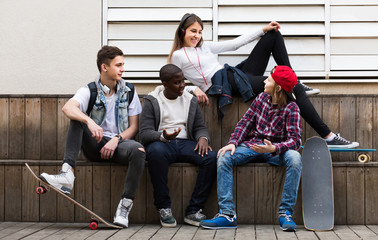 girl and three boys hanging out outdoors and discussing something