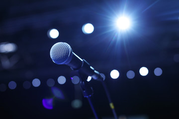 Wall Mural - Close up of microphone in concert hall or conference room with cold lights in background.