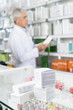 © Tyler Olson - Boxes On Counter With Chemist Working In Pharmacy