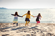 © Lisa Tichané - Three girls running hand in hand on a sandy beach