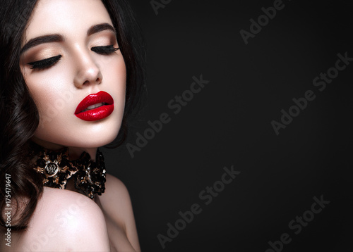 Zdjęcie XXL Piękna kobieta portret. Młoda dama pozuje zakończenie up na czarnym tle. Seksowny makijaż, czerwona szminka. Wspaniała biżuteria na szyi.
