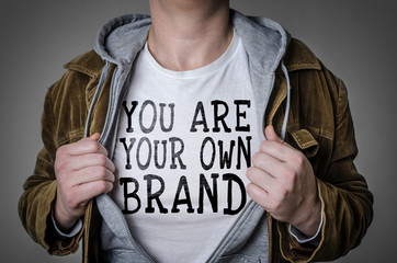 man showing you are your own brand tittle on t-shirt. personal branding concept.