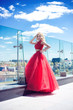 © Dziana - beautiful young girl on the roof of a building in a red lush dress