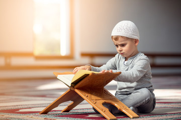 The Muslim child prays in the mosque, the little boy prays to God, Peace and love in the holy month of Ramadan.