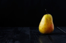 Yellow Pear On A Black Background And A Wooden Table