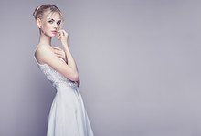 Fashion Portrait Of Beautiful Young Woman With Blond Hair. Girl In White Dress On White Background