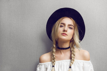 close up of beautiful young blonde woman with black hat. her hair is tied in two big ponytails. arou