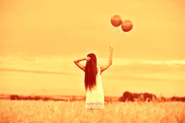 Dream, happiness - young girl in a field with flying balloons