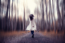 Young Woman In A Trench Coat Walks In Autumn Park