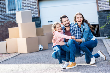 family sitting in front of new house