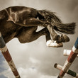 A strong black horse is jumping over the barrier