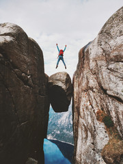 Wall Mural - Man jumping over Kjeragbolten Travel in Norway Kjerag mountains extreme vacations adventure tourist happy emotions success concept
