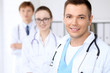 © rogerphoto - Cheerful smiling male doctor with medical staff at the hospital