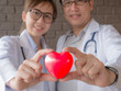 © Mongkolchon - The acting setup of medical work. The Asian young male and female medical doctors carry red heart shape model in their hands in the concept of care your heart. Selective focused