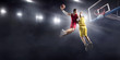 © Alex - Basketball player makes slam dunk on big professional arena. Player flies through the air with the ball. Opponents try to prevent the ball from hitting the basketball ring.